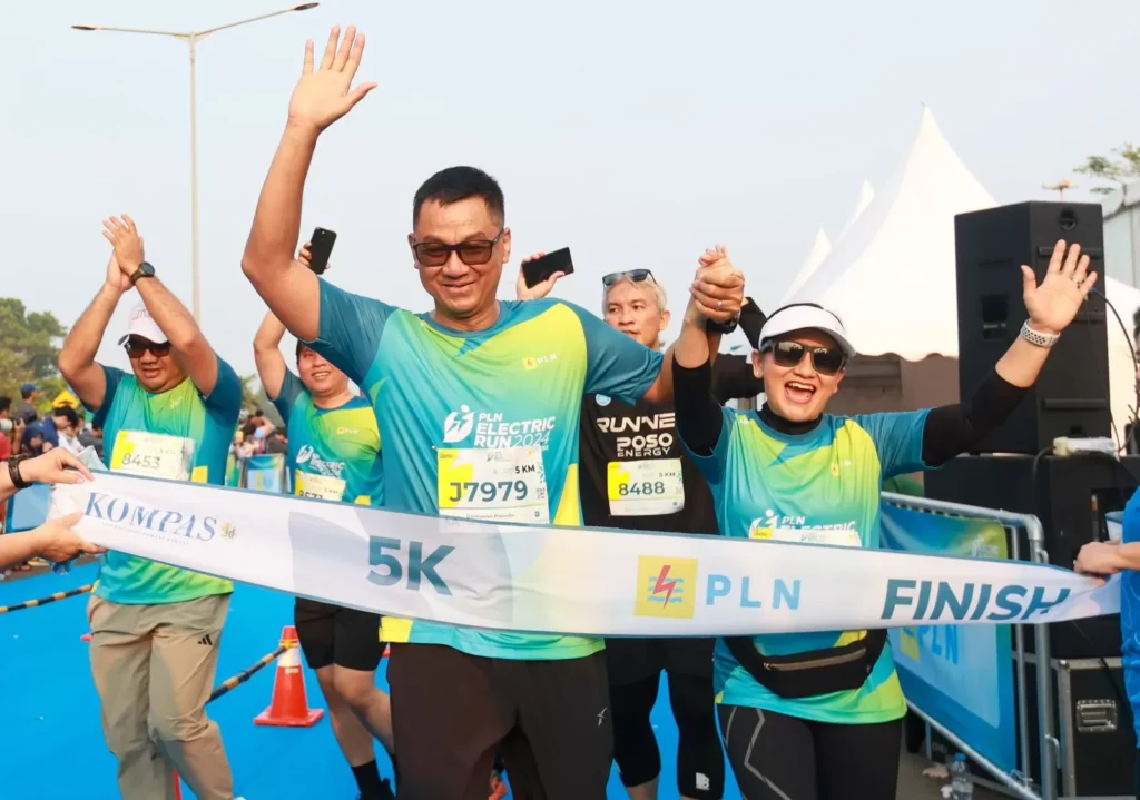 Direktur Utama PLN, Darmawan Prasodjo (kiri) bersama istri, Diny Darmawan Prasodjo (kanan) saat melintasi garis finish dan menyelesaikan PLN Electric Run 2024 kategori 5K.