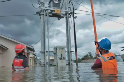 Petugas PLN bertugas di tengah banjir.